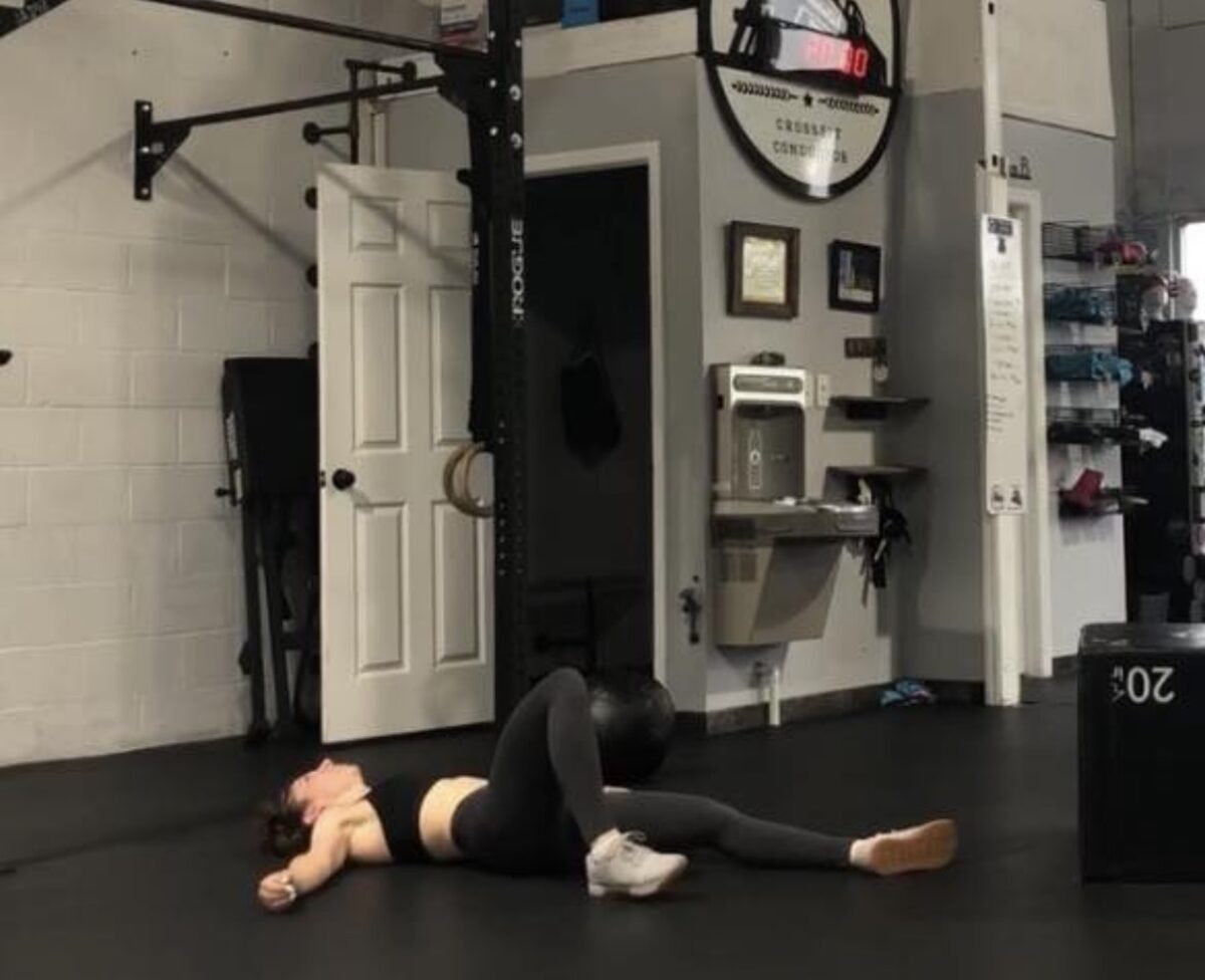 Amanda lying exhausted on the gym floor after a workout